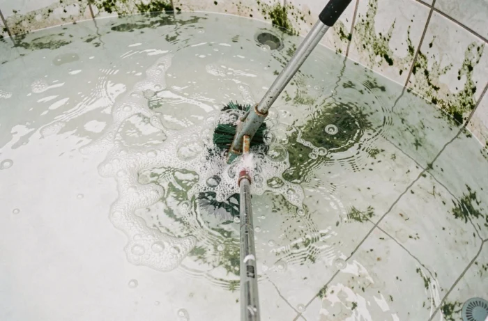 Brossage des parois d'une piscine dont l'eau est saturée et trouble pour éliminer les algues