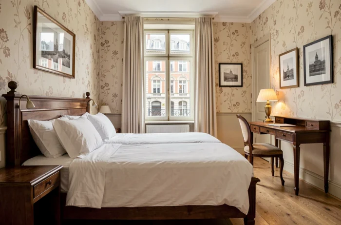 Chambre d'hôtel boutique confortable à Bruxelles avec lit double en lin blanc et vue sur des façades Art Nouveau