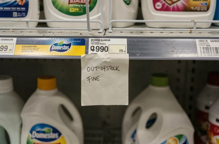 Gros plan sur une étiquette de rayon Domestos avec mentions de rupture de stock et étagères presque vides